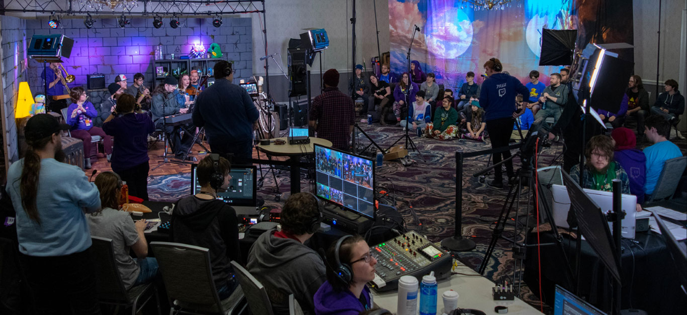 An event in 2020, showcasing a complete stage with an audience, lighting, mixers, cameras, and a dedicated production crew